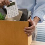 Persona empacando objetos personales de oficina en una caja tras un despido laboral